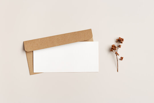 Top view blank white paper card and craft paper envelopment, autumn letter  with copy space for text, autumn greeting or invitation card with trend dry flower, fall beige brown colors still life