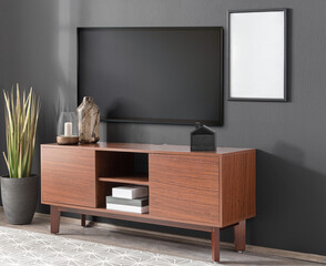 An attractive wooden entertainment center with shelves and cabinets stands, Blank picture frame mockup hanging on wall