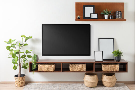 a TV room and frame on a wall in a living room, Set of black portrait picture frame mockups, featuring wicker baskets and various green plants