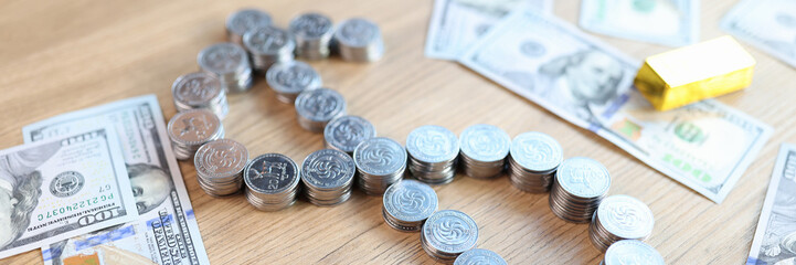 Gold bars, dollar banknotes and dollar sign shaped stacks of coins on table.