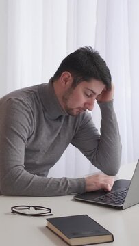 Vertical video. Work pressure. Exhausted employee. Job burnout. Tired weary unhappy business man stressed with deadline overwork lack of sleep at laptop modern office desk.