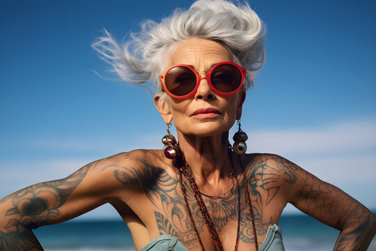 portrait of a retired senior woman with tattoos in sunglasses on the beach