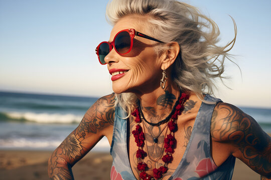 portrait of a retired senior woman with tattoos in sunglasses on the beach