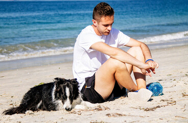 relaxed young man on the beach with his dog