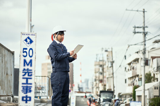手元を見ている作業服とヘルメットの男性
