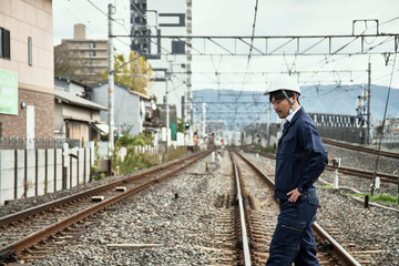 線路を渡る作業服とヘルメットの男性