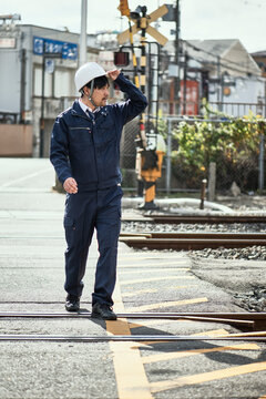 線路を渡る作業服とヘルメットの男性
