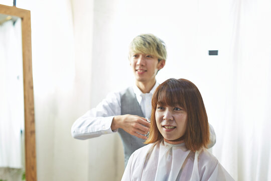 客と会話しながら髪を切る美容師