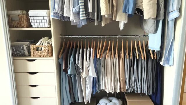 Wardrobe with perfect order clothes in blue and light shades on the hangers and things in containers. The concept of organization of space, storage of clothes and order in the house. 