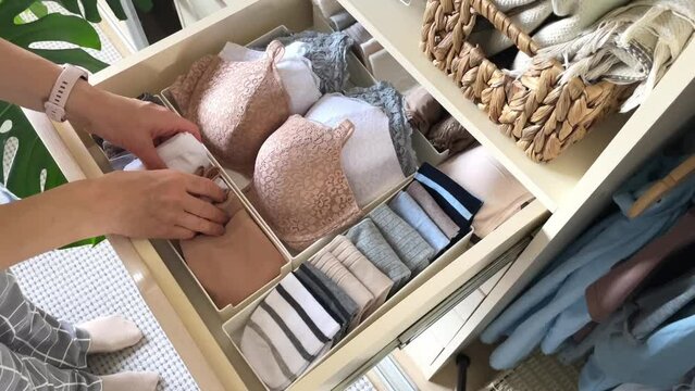 An unidentified neat housewife takes underwear, socks, panties and a bra from a closet drawer. The concept of organization, storage and order. 