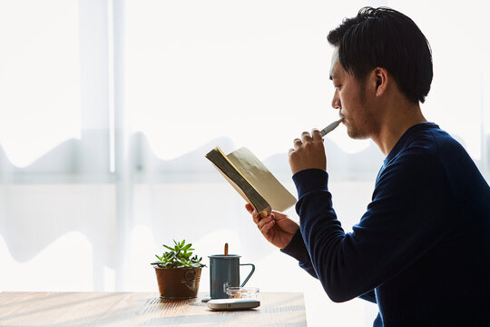 カフェで本を読みながらアイコスを吸う男性