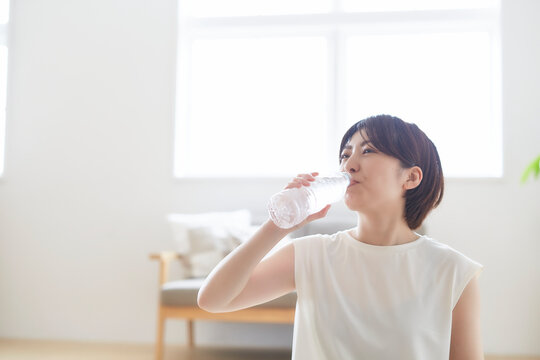 室内でペットボトルで水分補給する女性