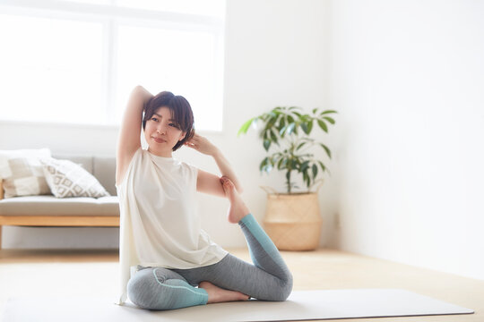 室内の床でヨガのポーズをとる女性