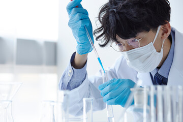 白い空間で実験をしている白衣を着た男性