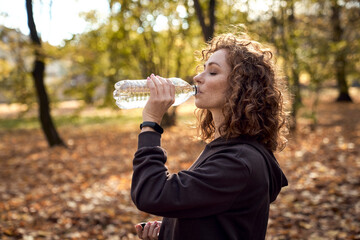 Side view of caucasian ginger woman drinking water