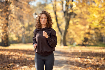 Caucasian woman jogging in the park in the autumn   during sunny weather