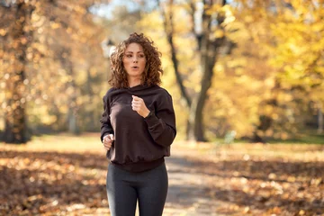 Deurstickers Caucasian woman jogging in the park in the autumn   during sunny weather © gpointstudio