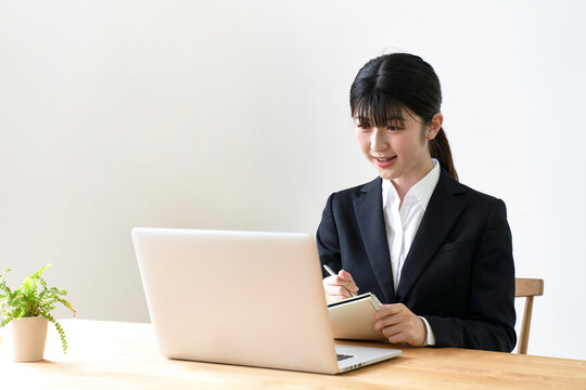 パソコンでのオンライン面接でメモを書き留める女子の就活生