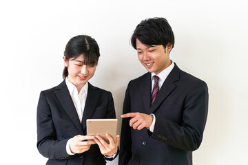 iPadを操作するスーツ姿の男女の学生