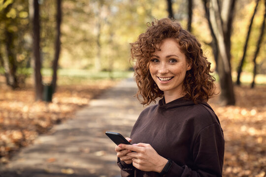 Portrait of caucasian woman browsing mobile phone with fun during the jogging activity
