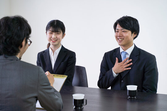 集団面接で面接官と会話をする男子の就活生