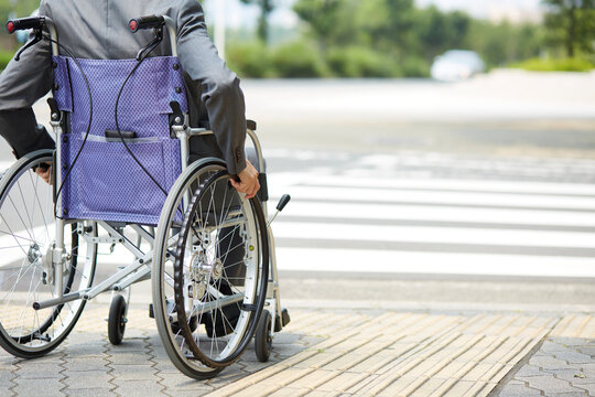 車椅子に乗るスーツ姿の男性と道路