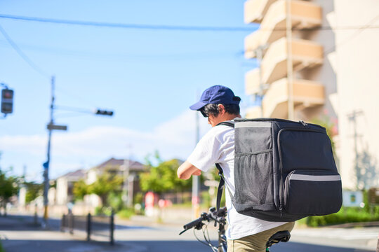 自転車でフードデリバリーをする配達員の後ろ姿