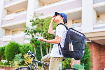 携帯を持ったフードデリバリーの配達員