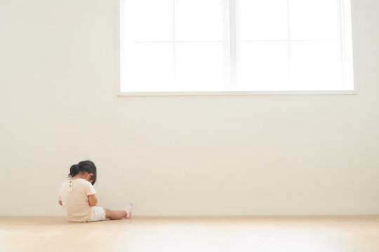 部屋の隅に座る子供の後ろ姿