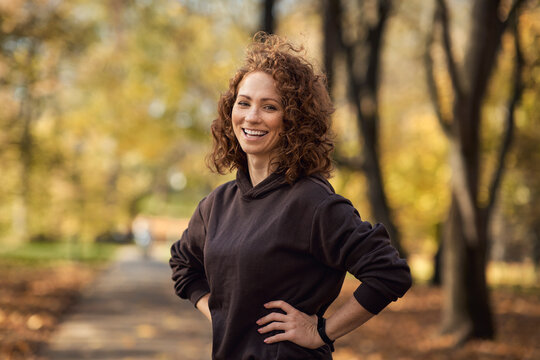 Portrait of cheerful caucasian woman wearing sports clothes and standing in the autumn park
