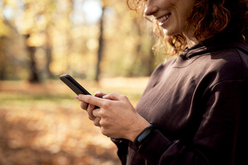 Caucasian woman browsing mobile phone with fun during the jogging activity
