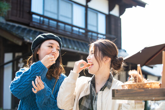 観光地のお店で栗を食べる女性２人