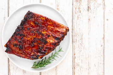 roasted barbecue pork spare ribs with honey, oregano and rosemary in simply white ceramic plate on white old wood texture background with copy space for text, top view