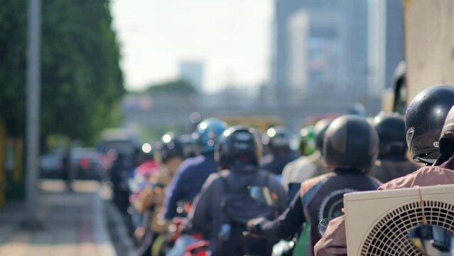 blur image of Jakarta's urban traffic density dominated by motorcycles. Depicts high pollution, heat, and congestion. Taken with a telephoto lens and handheld