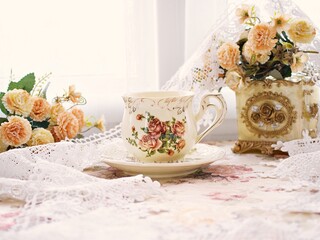 Antique cup of tea with saucer ,yellow orange rose flowers background ,porcelain vintage style ,old English coffee cup still life for wallpaper ,romance roses backgrounds 