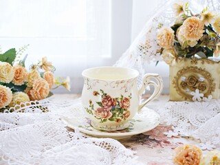 Antique cup of tea with saucer ,yellow orange rose flowers background ,porcelain vintage style ,old English coffee cup still life for wallpaper ,romance roses backgrounds 