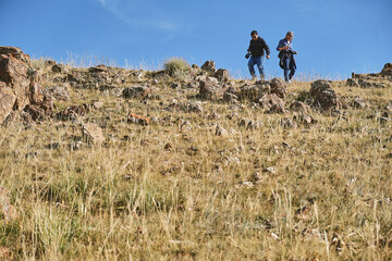 Couple travelers gently descend the hill, wide angle