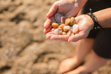 Woman's hands holding rocks and beach glass collected on beach