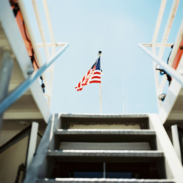View from below deck on a boat, looking up stairs at an American flag