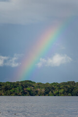 Beautiful view to rainbow over green rainforest river and clouds