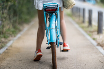 Un vélo éléctrique bleu vue de l'arrière avec une cycliste dessus qui pédale - obrazy, fototapety, plakaty