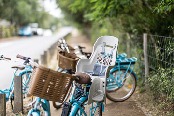 Vélo avec siège de transport pour enfants, porte bébé.  Sport familial sécurisé, vélo en photo le long d'une piste cyclable sous des arbres - obrazy, fototapety, plakaty