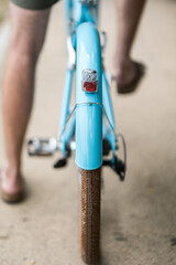 Un vélo bleu vue de l'arrière avec un cycliste dessus qui pédale