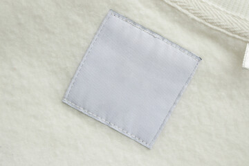 Blank white laundry care clothes label on fabric texture background