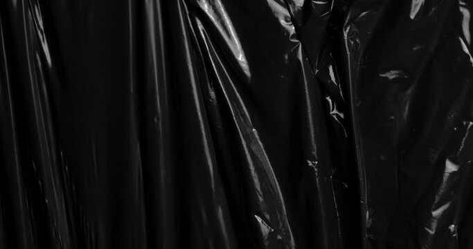 Engage with the captivating interplay of textures as a stretched plastic film graces a black background, resembling the crumpled appearance of cellophane wrap often used for packaging food items.