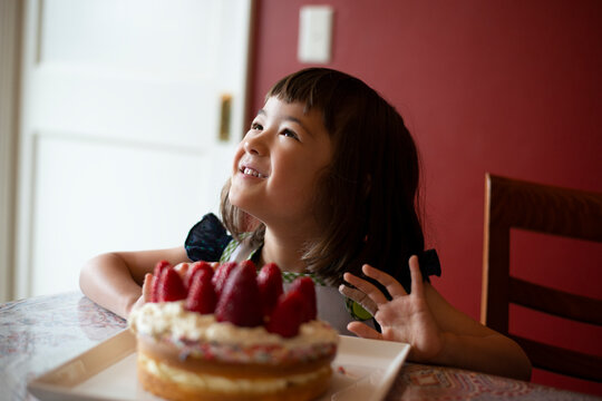 いちごのケーキの前で笑っている女の子