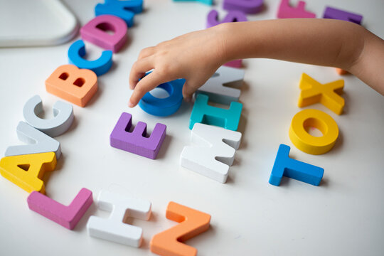 アルファベットの木のおもちゃで遊んでいる子供の手元