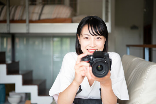 一眼レフカメラを構えて笑っている女性
