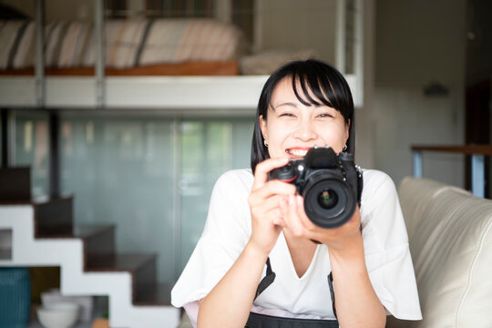 一眼レフカメラを構えて笑っている女性