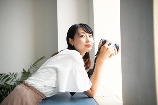 一眼レフカメラを構えてこちらを見ている女性